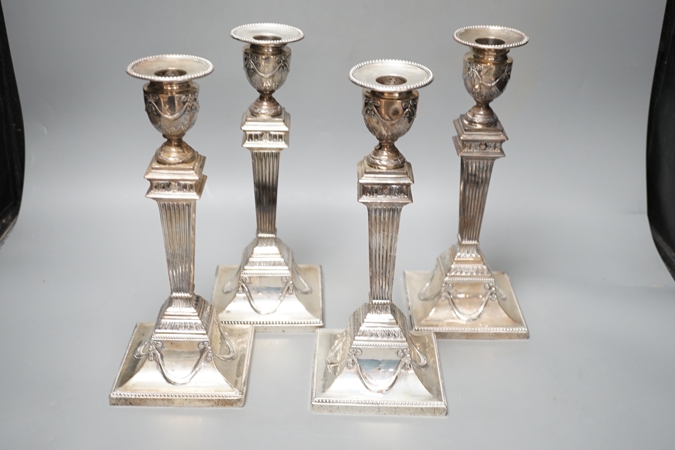 A set of four late Victorian silver candlesticks, with fluted, tapered stems, Hawksworth, Eyre & Co, Sheffield, 1890, 27.5cm, weighted (a.f.).